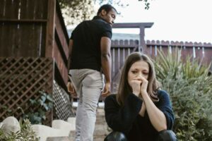 couple triste - femme assise en larmes, homme qui s'éloigne
