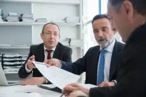 Un groupe de trois hommes en costume examinant des documents dans un bureau